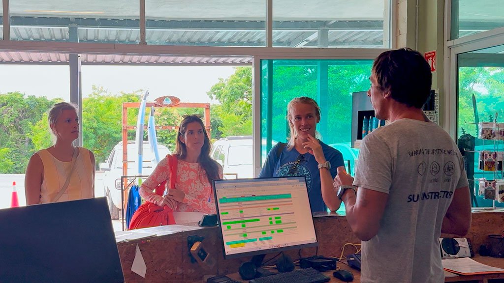 Front Desk Agent Job at Wildmex – Nayarit Mexico Wildmex staff explaining surf lessons to female surfers at reception in Nayarit Mexico