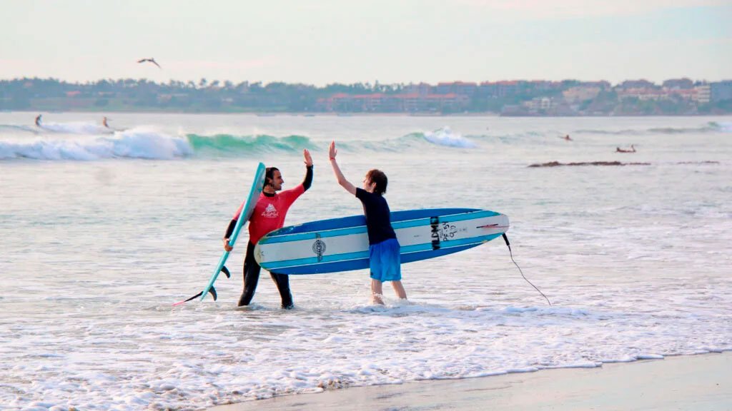 Surf Photographer A WildMex surf instructor and a happy guest exchanging a high five on the beach after a successful water session.